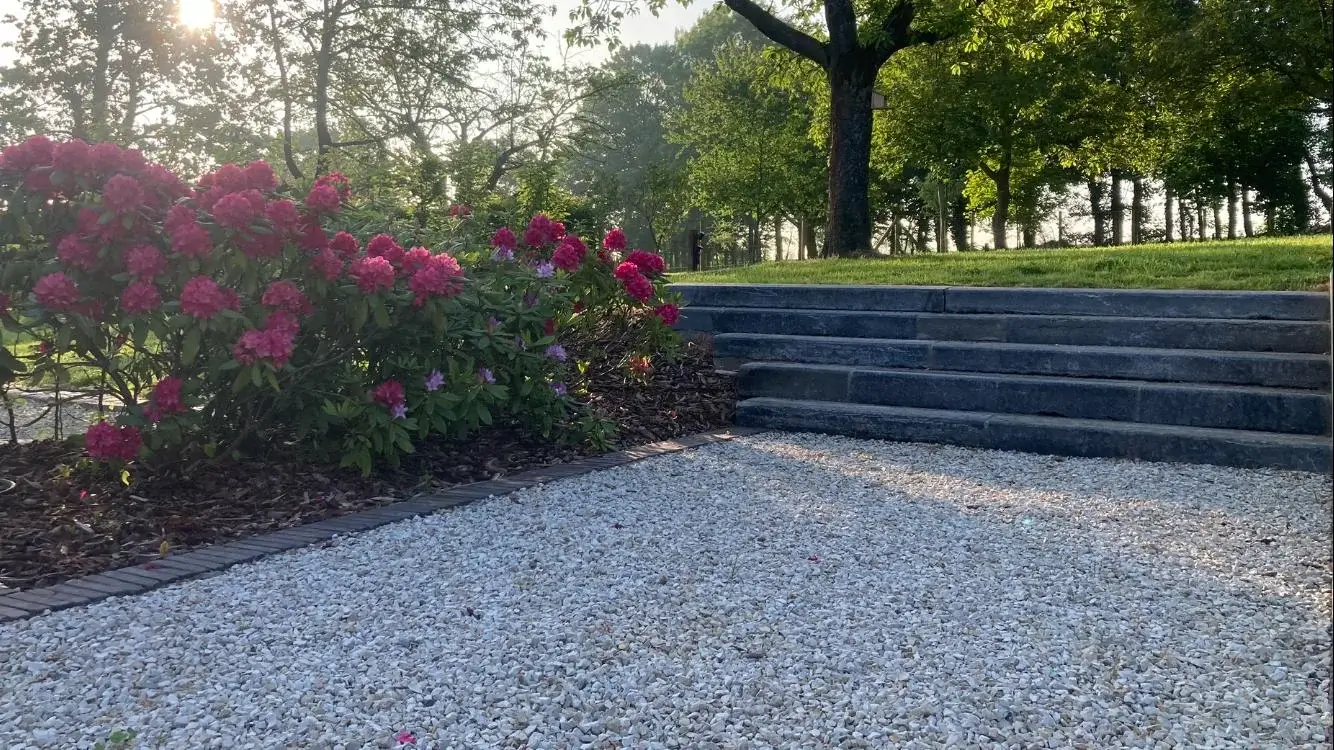 Belle allée surmontée d'un escalier extérieur et entourée de parterres de fleurs